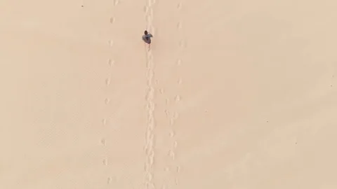 Aerial Drone Flys Overhead Tracking Athletic Man Running on Sand Dunes at Beach Stock Footage 125294224