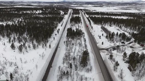 Aerial drone footage captures a red truck winding through the snow covered Stock Footage 330376764