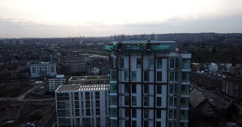 Aerial drone footage of construction workers outside of a glass skyscraper. Stock Footage 86010879