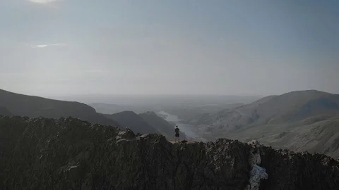 Aerial drone footage of a man climbing mountain ridge Stock Footage