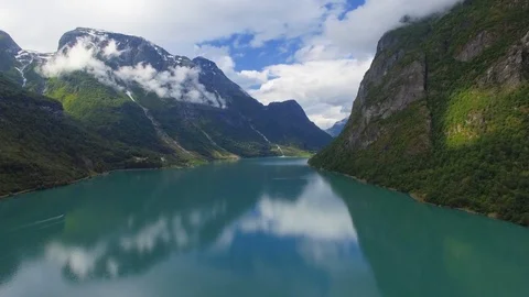 Aerial drone footage over a lake with surrounding mountains Stock Footage
