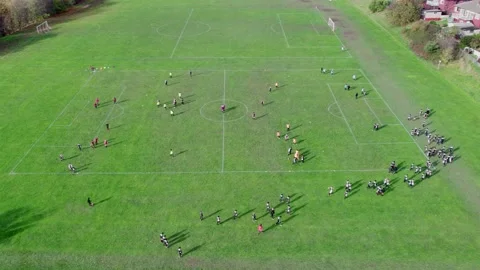 Aerial drone footage of playing fields, football pitch with school children.. Видео 235675136