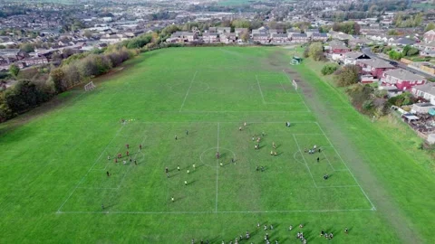 Aerial drone footage of playing fields, football pitch with school children.. Видео 235675180