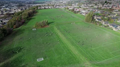 Aerial drone footage of playing fields, football pitch with school children.. Видео 235675222