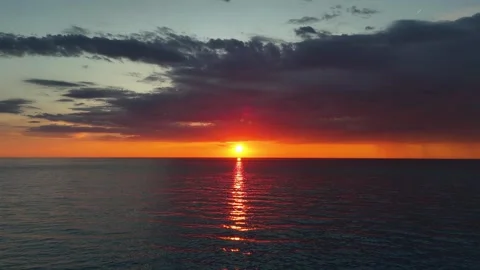 Aerial drone footage pulling backward and upward over a calm sea during sunset Vidéo 336719955