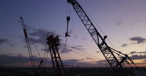 Aerial drone footage of a tower crane and construction worker at sunset. Vidéo 82017009