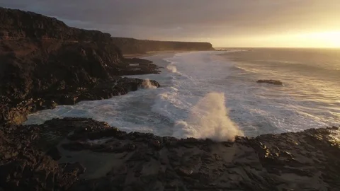 Aerial Drone Footage Of Waves Crashing Against Rocks During Sunset Stock Footage