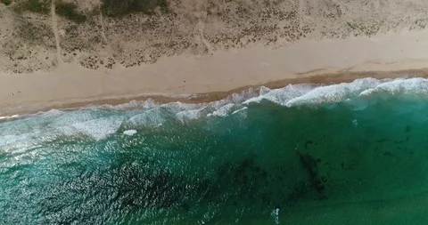 Aerial drone footage of waves reaching shore. Beach on top view. Stock Footage