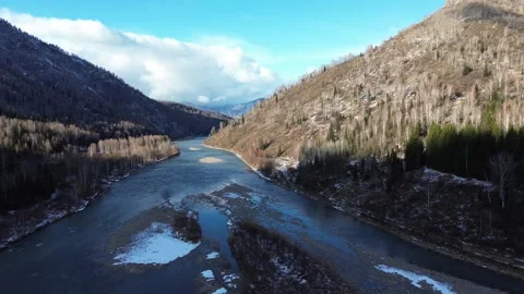 Aerial Drone Forward Flight Over a Winding Mountain River in a Snowy Valley Stock Footage 348520368