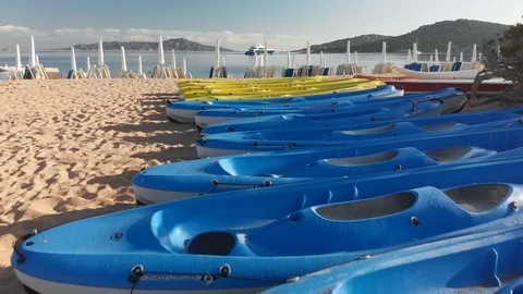 Aerial drone forward view of an empty beach through kayaks, umbrellas and yacht Stock Footage 126612976