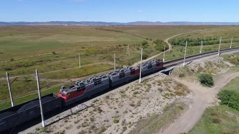 Aerial drone freight train rides along the road and the river Stock Footage 98043244