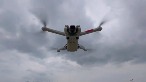 Aerial drone hovering in cloudy sky with propellers spinning, captured from Stock Footage 319556623