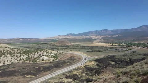 Aerial drone hugging hillside moving towards highway Stock Footage 139930779
