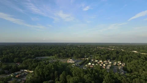 Aerial Drone low hover over Suburb surrounded by lush green landscape Stock Footage 139930873