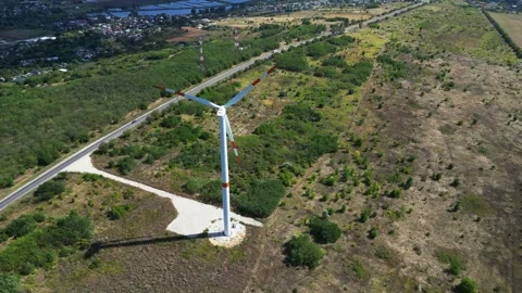 Aerial drone orbit around wind turbine near road and village in Moldova Stock Footage 320371028