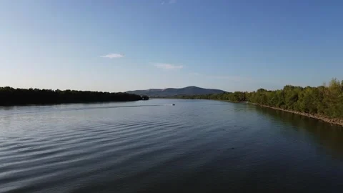 Aerial Drone Orbiting Over River with Distant Motorboat and Forested Mountains Stock Footage 313830682