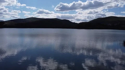 Aerial drone over cold water lake with mountain in the background Stock Footage