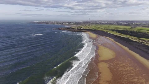Aerial Drone Over Ocean Waves and Sandy Beach with Coastal Town Video stock 333784368