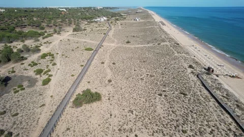 Aerial drone overlooking beach dunes with wooden paths near Faro, Algrave Stock Footage 244536494