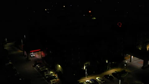 Aerial: Drone Panning Red Text Illuminating Outside Hospital In City At Night - Stock Footage 236967425