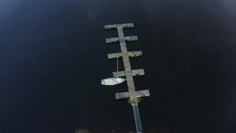 Aerial drone panoramic orbit around a floating lake dock with a moored white yac 스톡 동영상 321125958