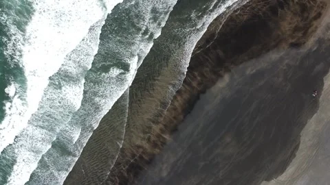 Aerial Drone Parallel Flight Over Waves and Volcanic-Sand Beach Video stock 317470312
