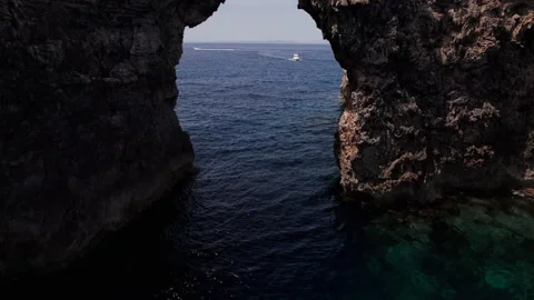 Aerial drone passing through menorca large hole shaped Pont d'en Gil Stock Footage 238993756