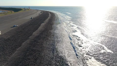 An aerial drone perspective captures the expansive stone and asphalt sea dike 库存影片 335317758