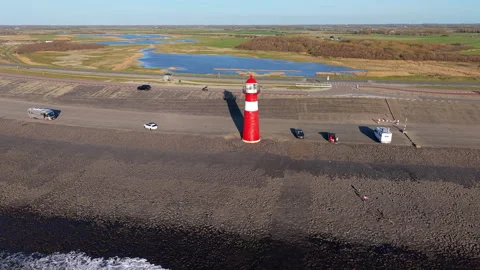 An aerial drone perspective captures the red and white Noorderhoofd lighthouse Stock Footage 335317573