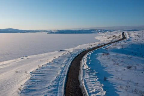 Aerial drone perspective of a winding cleared winter road curving past a Stock Photos
