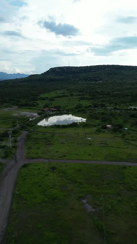 Aerial drone of a pond reflecting clouds in green fields, central Mexico Stock Footage 341548187