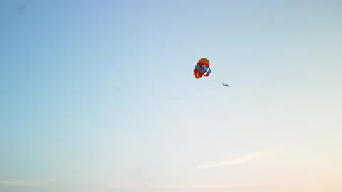 Aerial Drone POV of a skydiver with a fully open multi colored Parachute Stock Footage 242538760