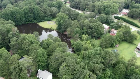 Aerial drone pull away from brown lake summer time with green trees neighborhood Stock Footage 170572293
