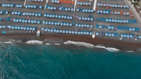 Aerial drone pull back revealing sandy beach rows of umbrellas, swimming people Stock Footage 113706297