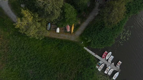 Aerial drone pull up camera flies high from boat berth dock near trees and grass Stock Footage 114036630