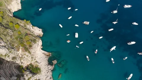 Aerial drone pull down luxury boats berth in crystal clear sea water rock cliffs Stock Footage 113699691