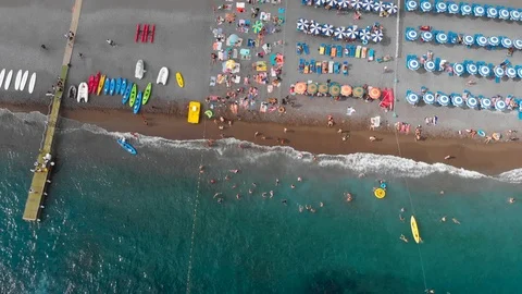 Aerial drone pull down sandy beach with rows of umbrellas - swimming people Stock Footage 113703938