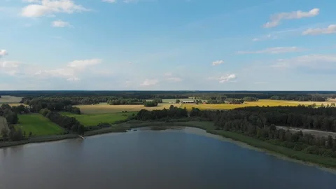 Aerial drone pull up from lake to stunning landscape with agricultural fields Stock Footage 114036086