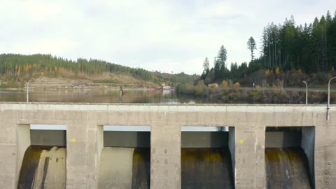 Aerial drone pullback from a mountain lake dam with a hiker in a beanie walking  Vídeos de archivo 321147979