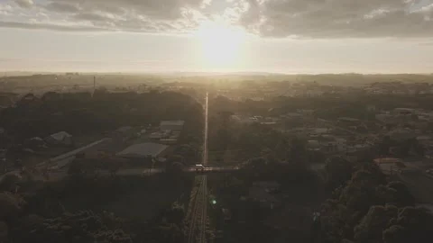 Aerial drone pullback over railway aligned with sunrise and road bridge Vídeos de archivo 333385240