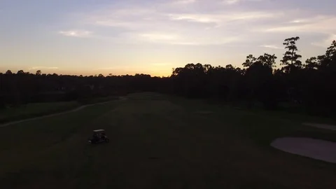 Aerial Drone Pulling Away from Golf Cart on Neighborhood Fairway at Sunset wi Video stock 79548248