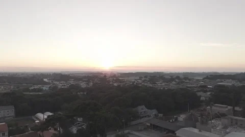 Aerial drone pulling back from sunrise over suburban city at dawn Vídeos de archivo 334556315