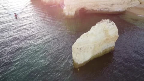 Aerial Drone Reverse Shot of Ocean, Rock, Boat, and Beach Stock Footage 249228011