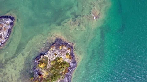 Aerial drone rotating down towards blue lake and rocky shoreline Video stock 235756211