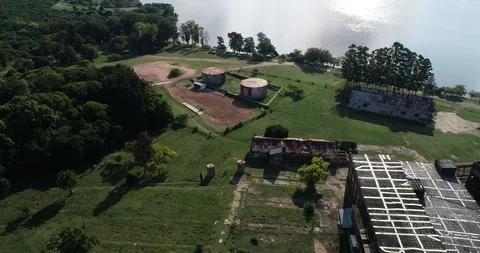 Aerial drone scene flying from rusty industrial sheds passing above old silos 스톡 동영상 119026865