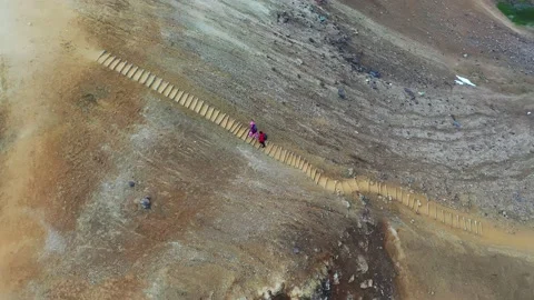 Aerial drone shot of active couple hiking long trail path in sunny day. Stock Footage 171232017