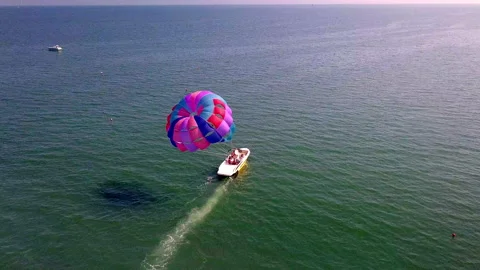 Aerial drone shot of boat pulling parachute over the sea in lignano parasailing Stock Footage 233645285