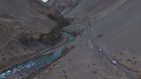 Aerial drone shot capturing a white car driving along a remote mountain road in Stock Footage 304949720