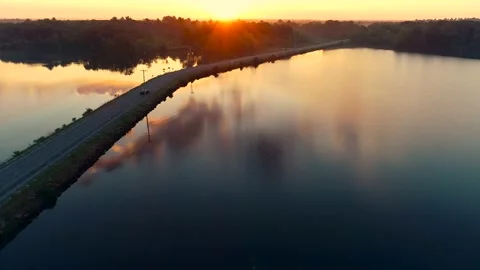 Aerial drone shot car drives on bridge over lake at sunrise 4K Stock Footage