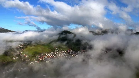 Aerial drone shot of clouds moving above mountain village during morning with Stock Footage 319828524